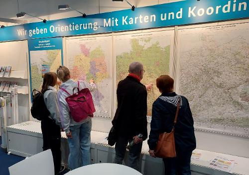Foto zeigt den BKG-Stand auf der Leipziger Buchmesse. Besucher stehen vor Wandkarten.